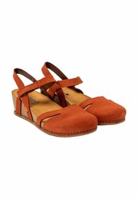 Sandalias de cuña de gamuza marrón con dos tiras cruzadas, punta descubierta y diseño con recortes. Cuenta con una plantilla texturizada y acentos cosidos.