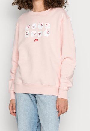 Helles rosa Sweatshirt aus Baumwollmischung. Mit einem grafischen Design "NIKE LOVE" in Rot und Weiß, sowie gerippten Bündchen und Saum.