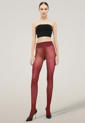 Røde ugennemsigtige strømpebukser med en let gennemsigtig effekt, med høj talje og glat tekstur. Båret med en sort stropløs top og høje hæle.