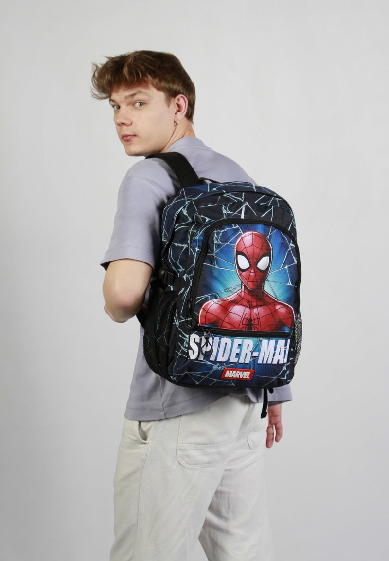 Un sac à dos noir avec un grand motif de Spider-Man, un motif de toile bleu, des zips doubles et des bretelles ajustables. Le matériau semble durable.