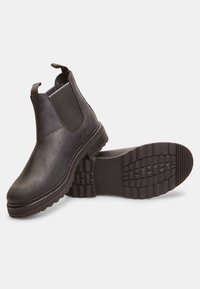 Botas de cuero negro hasta el tobillo con paneles laterales elásticos, lengüetas en la parte superior y suela de goma texturizada con un patrón de banda de rodadura robusto.