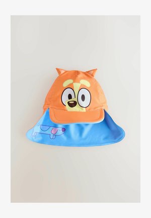 Casquette orange avec un visage de chien cartoon, présentant des oreilles tombantes et de grands yeux. La visière bleue comporte une image imprimée d'un chien. Matériau lisse et léger.