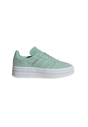 Zapatillas de ante verde claro con una lengüeta texturizada, suela blanca en capas y diseño de tres franjas. "Gazelle" está impreso en dorado en el lateral.