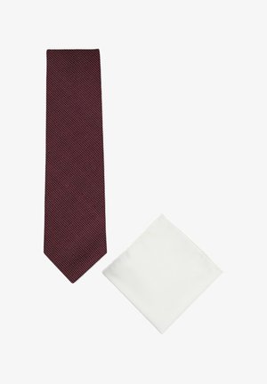 Bordeauxrote Krawatte mit kleinem weißem Punktmuster neben einem schlichten weißen gefalteten Einstecktuch auf weißem Hintergrund.
