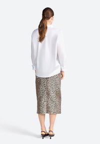 Chemise blanche à manches longues, associée à une jupe crayon imprimée léopard et des talons noirs. Mettez l'accent sur le tissu lisse et le design ajusté.