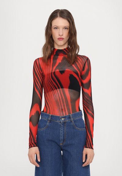 Haut en mesh à manches longues rouge et noir avec un motif tourbillonnant, design ajusté, col haut, associé à un jean en denim taille haute.
