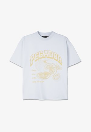 Tricou alb cu maneci scurte, având un design grafic galben cu cuvântul "PEGADOR" și ilustrații de fructe citrice, împreună cu text dedesubt.