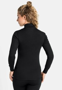 Black long-sleeve turtleneck top made of stretchy fabric, fitted design, smooth texture, features a high neckline and long sleeves.