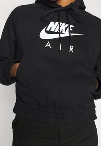 Black Nike Air hoodie with a drawstring hood, elasticized cuffs, and a cinched waistband. Features a large white logo on the front.