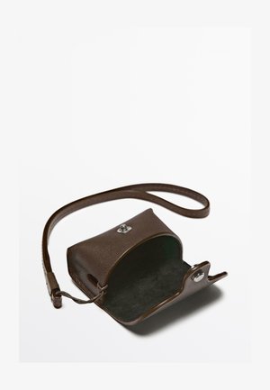 Braune Leder-Crossbody-Tasche mit strukturierter Außenseite, einem silbernen Druckverschluss und einem weichen, dunklen Innenraum. Enthält einen schlanken, verstellbaren Trageriemen.