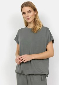 Løsgribende grå bluse med korte ærmer, rund halsudskæring og samlet kant med snoretræk. Fremstillet af blød, glat stof.