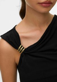 Top senza maniche di colore nero con tessuto arricciato sulla spalla, accentuato da tre anelli dorati che creano un effetto drappeggiato. Texture liscia.