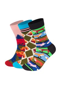 Trzy pary kolorowych skarpetek: różowe w wzór drzew, zielone w romby z wiewiórkami oraz czarne z grafiką lisów na jasnym tle.