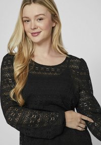 Mustmust läbipaistva pitsiga top pikonde ja puhvletattega. Muster pitsikujundus sisaldab lille- ja geomeetrilisi motiive. Ümara kaelusega, pehme tekstuur.