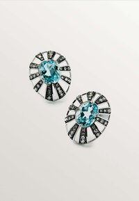 Pendientes de tono plateado que presentan una gema ovalada azul, rodeada de acentos negros y un diseño de rayas radiante.