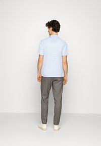 Light blue short-sleeve shirt paired with gray trousers. The shirt features a relaxed fit, and the trousers have a tailored silhouette.