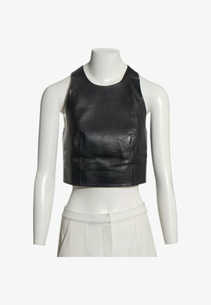 Zwart leren mouwloze cropped top getoond op een witte mannequintorso die witte hoog getailleerde broeken draagt.