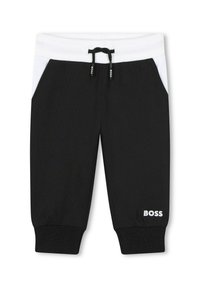 Pantalon de survêtement noir avec taille et accents latéraux blancs, doté d'un cordon de serrage et d'un logo "BOSS" brodé sur la jambe inférieure. La texture est douce.