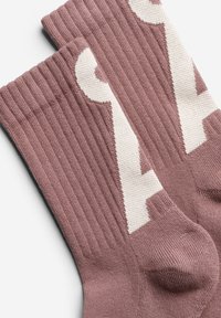 Socken in gedämpftem Mauve mit gerippter Textur. Mit einem weißen Logo-Muster. Material aus Baumwollmix mit verstärkter Zehen- und Fersenpartie.