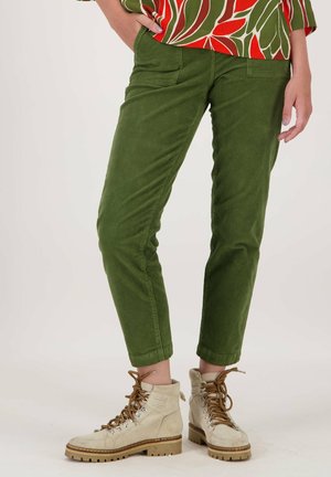 Groene corduroy broek met een slim fit, voorzakken en opgerolde boorden, gecombineerd met beige veterlaarzen met een robuuste zool.