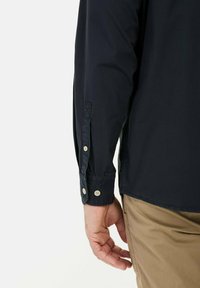 Marineblauwe longsleeve shirt met knoopmanchetten, met een gladde textuur en een getailleerde pasvorm, gecombineerd met khaki broeken.