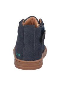 Navy suède enkelboot met een bruine rubberen zool, voorzien van een ritssluiting en twee groene decoratieve stippen op de hiel. Zachte beige binnenvoering.