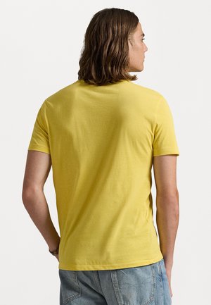 Yellow crewneck T-shirt made of cotton. Short sleeves, regular fit, smooth texture, no visible patterns or accents. Back view shown.