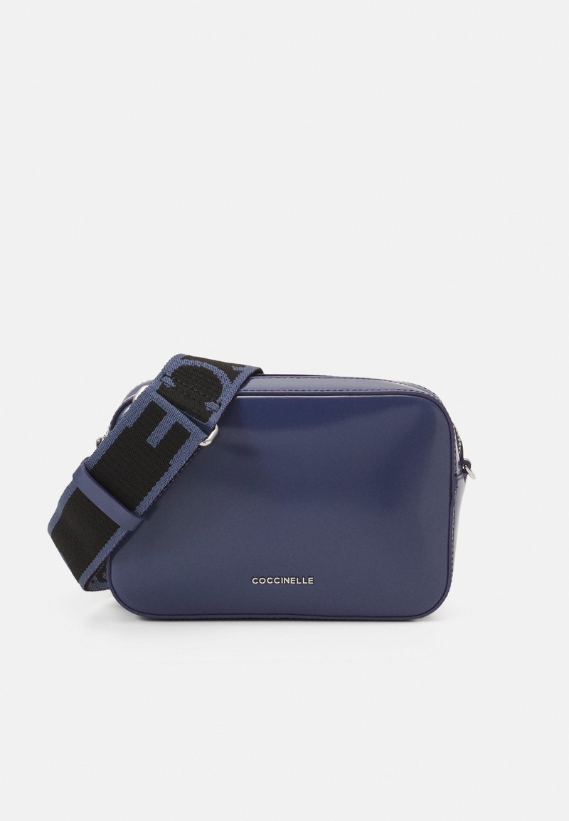 Borsa a tracolla blu navy con una texture liscia, dotata di una tracolla nera con accenti del logo e chiusura con zip. Nome del marchio esposto sulla parte anteriore.