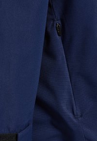 Tissu bleu marine avec un motif texturé, comportant un détail de fermeture éclair et une poche. Le matériau semble durable et résistant aux intempéries.