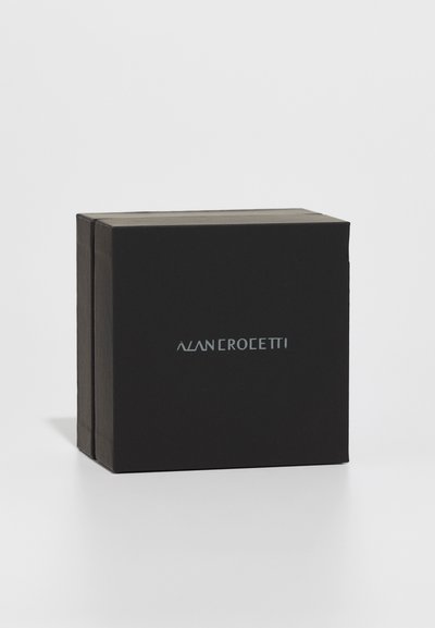 Sort rektangulær kasse med en glat overflade, der har et metal-logo på forsiden. Minimalistisk design, lukket uden synligt hardware.