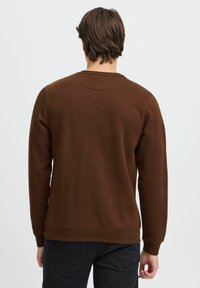 Brun sweatshirt med lange ermer, rund hals og ribbede mansjetter. Glatt tekstur med ensfarget og minimal design. Ingen synlige logoer eller mønstre.