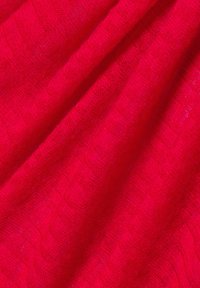 Helles rotes, strukturiertes Gewebe mit einem gerippten Muster, das eine weiche und leichte Webart zeigt. Falten verleihen Tiefe und visuelles Interesse.
