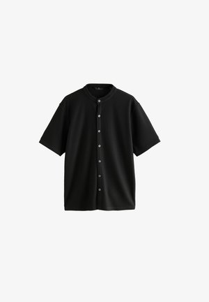 Chemise noire à manches courtes avec un col rond, présentant une texture côtelée et cinq boutons sur le devant pour la fermeture.