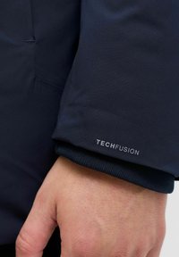 Ärmel der navyblauen TechFusion-Jacke mit glatter Textur, elastischen Bündchen und dezentem Logodetail.