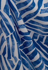 Tessuto di cotone con un motivo astratto blu e bianco caratterizzato da linee e forme audaci e curve, che mette in risalto la texture e il contrasto dei colori.