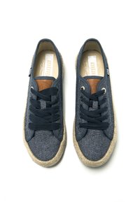 Zapatillas de lona azul marino con cordones redondos, ribete de yute tejido beige y un acento de cuero marrón en la lengüeta. Presenta seis ojales para los cordones.