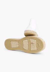 Espadrilles en toile blanche avec des accents de jute tressé et une semelle en caoutchouc, présentant un design plat et un bout arrondi. Détails de couture visibles.