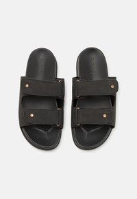 Sandales noires à glissière avec deux sangles ajustables, un matériel décoratif en cuivre et un semelle texturée pour une meilleure adhérence, dotées d'une semelle plate.