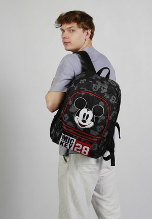 Mochila negra con un gran gráfico de Mickey Mouse, acentos rojos y un diseño de texto "MICKY 28". Hecha de material duradero con correas ajustables.
