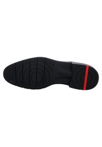 Schwarze Schuhsohle mit kreisförmigen und linearen Profiltiefen. Merkmale eines roten Akzents an der Ferse und einer strukturierten Oberfläche für besseren Grip.