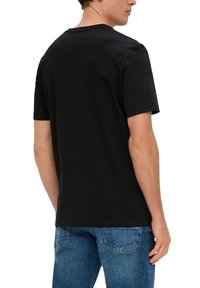 T-shirt en coton noir à manches courtes, col rond et coupe décontractée. Détails de couture visibles sur l'épaule et l'ourlet.