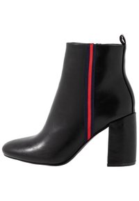 Bottine en cuir noir avec talon bloc et bande élastique latérale ornée de rayures rouges et bleu marine.