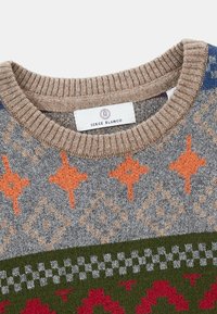 Col haut en tricot beige avec des côtes et des motifs géométriques en orange, gris, vert, bleu et rouge, arborant une étiquette Serge Blanco.