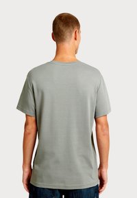 Grijs katoenen T-shirt met een ronde hals, korte mouwen en een gladde textuur, weergegeven vanaf de achterkant. Heeft een losse pasvorm.