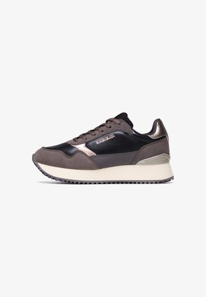 Sneaker sportivo con un mix di pelle nera liscia e suede grigio. Presenta dettagli metallici, una suola intermedia spessa color crema e una suola testurizzata.
