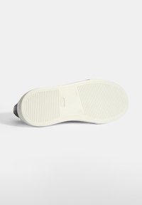 Weiße Sneaker-Sohle mit strukturiertem Gummidesign, das horizontale und vertikale Rillen für besseren Halt aufweist. Abgerundete Form mit glatten Kanten.