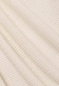 Gestrickter Stoff in weich-cremigem Weiß. Er weist ein strukturiertes Muster mit erhabenen, geschwungenen Linien und einem leicht dehnbaren Gewebe auf.