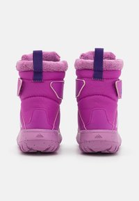 Bottines violettes mi-mollet avec un col duveteux, une sangle réglable et une semelle en caoutchouc texturée. Elles possèdent un talon plat et une doublure en tissu doux.