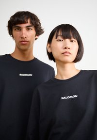 Salomon LOGO TEE UNISEX - T-shirt estampada - deep black
