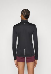 Juoda ilgomis rankovėmis palaidinė su stovu ant kaklo, nugaroje balta detalė. Derinama su bordosiomis šortais, lygios struktūros.